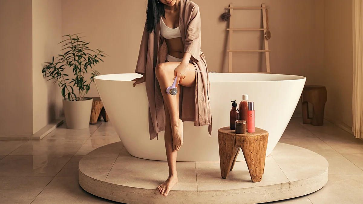 A fit woman in a bathrobe using PEACH 2 go in a gorgeous modern bathroom
